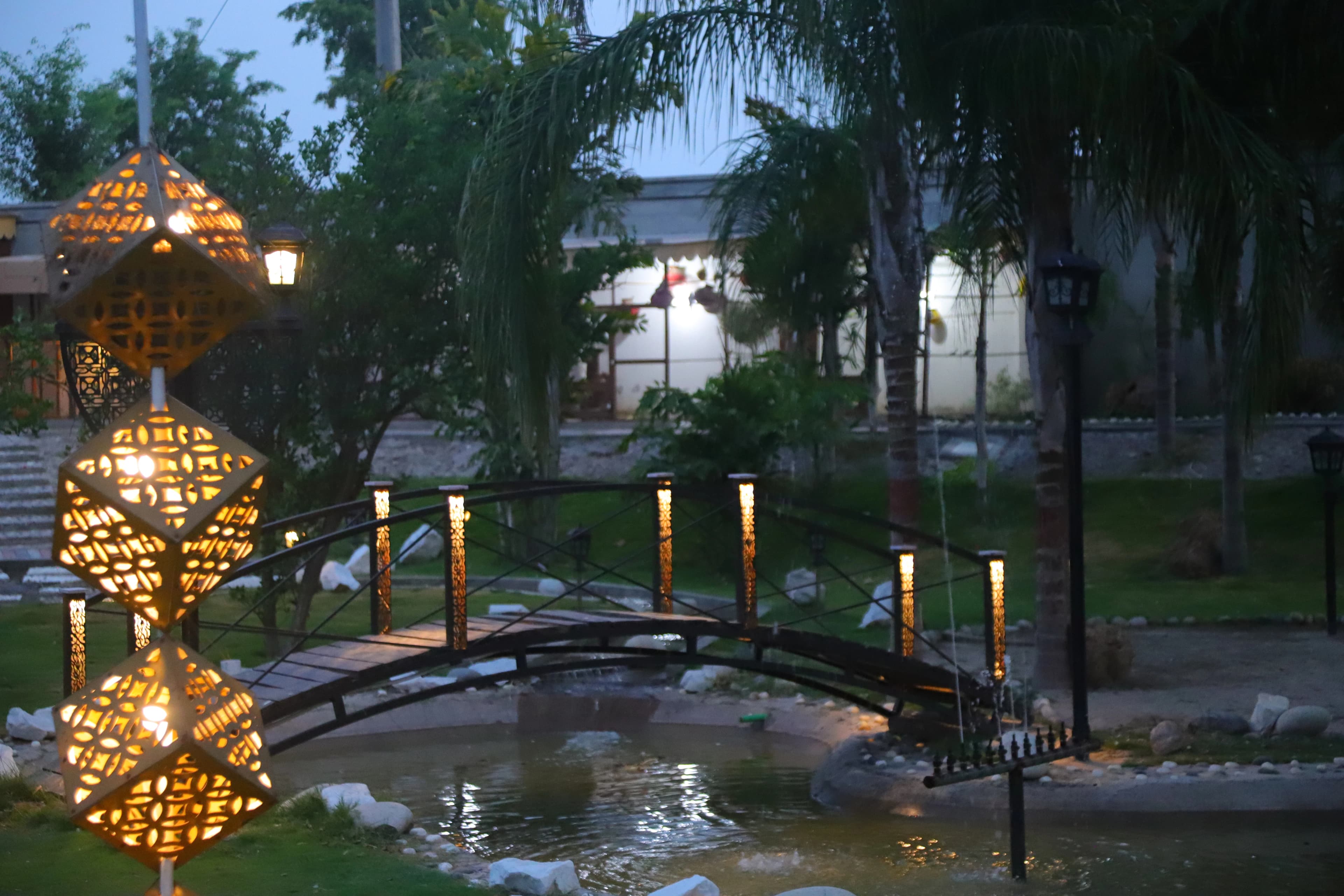 Close view of the bridge with glowing posts and garden backdrop